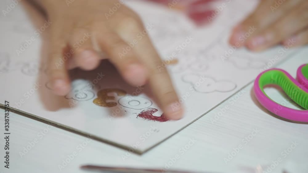 The child paints the paper drawings with shiny powder, rubbing small glitters on the basis of glue. Develops children's creativity The child paints the paper drawings with shiny powder, rubbing small glitters on the basis of glue. Develops children's creativity