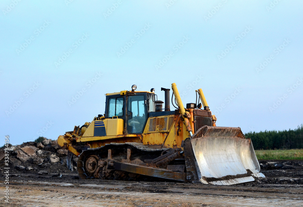 Dozer with bucket for pool excavation and utility trenching. Bulldozer during land clearing and foundation digging at construction site. Earth-moving equipment background Dozer with bucket for pool excavation and utility trenching. Bulldozer during land clearing and foundation digging at construction site. Earth-moving equipment background