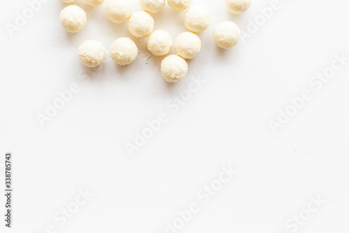 Coconut candy balls on white background top view copy space