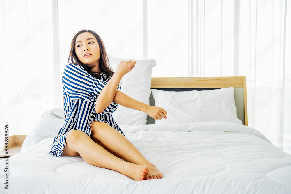 Beautiful young asian woman sitting on her bed in morning, stretching with arms raised after waking up, happy and relaxed after good night sleep,Healthy lifestyle, Wellness concept Beautiful young asian woman sitting on her bed in morning, stretching with arms raised after waking up, happy and relaxed after good night sleep,Healthy lifestyle, Wellness concept