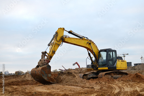 Excavator digs the ground for the foundation and construction of a new building. Road repair, asphalt replacement, renovating a section of a highway, laying or replacement of underground sewer pipes