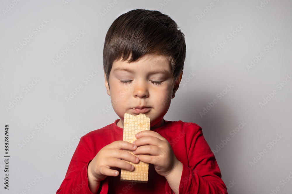 Little kid boy happily eats a crispy waffle. Happy baby and yummy. Little kid boy happily eats a crispy waffle. Happy baby and yummy.