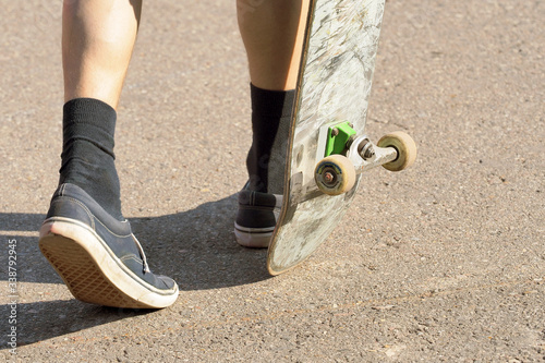 Subculture, teenager with a skateboard. Legs in socks and sneakers photo