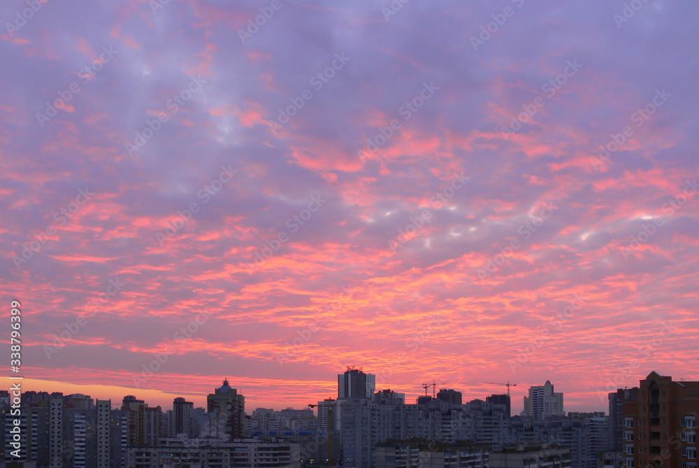 Bright multi-colored clouds over the city at sunrise
