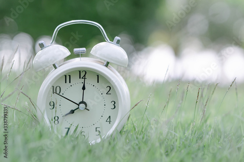 Alarm clock on fresh green gress background, morning relax time concept