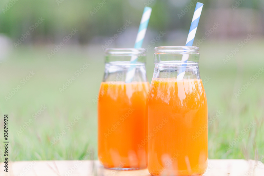 Closeup glass bottle of orange juice fruit on green grass nature background, food healthy concept Closeup glass bottle of orange juice fruit on green grass nature background, food healthy concept