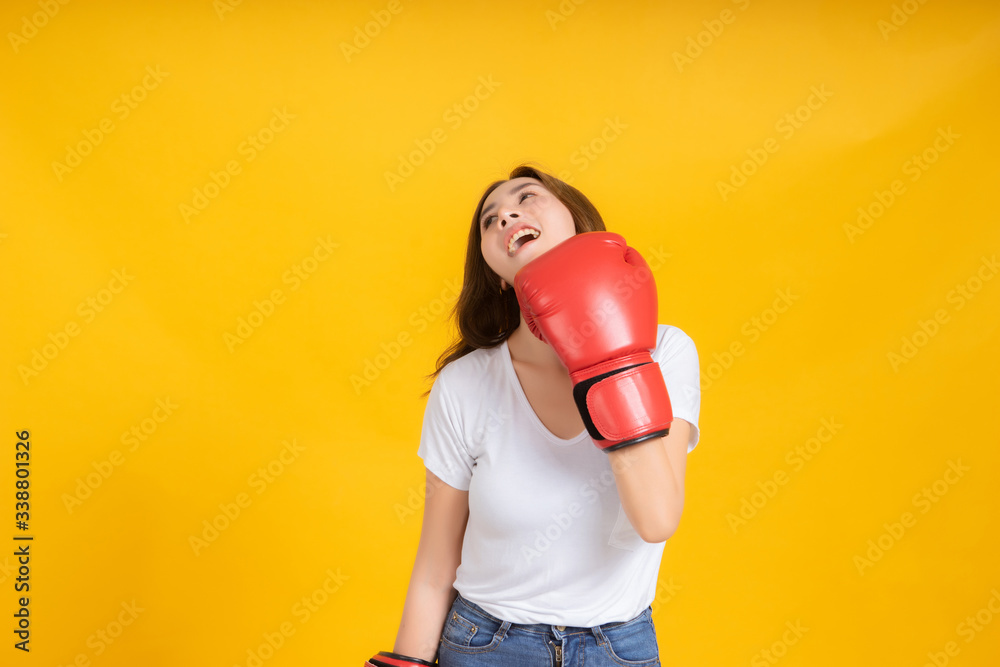 Portrait happy young asian woman with boxing glove self business knock out, punching hit in white t-shirt, Yellow background isolated studio shot and copy space. Portrait happy young asian woman with boxing glove self business knock out, punching hit in white t-shirt, Yellow background isolated studio shot and copy space.