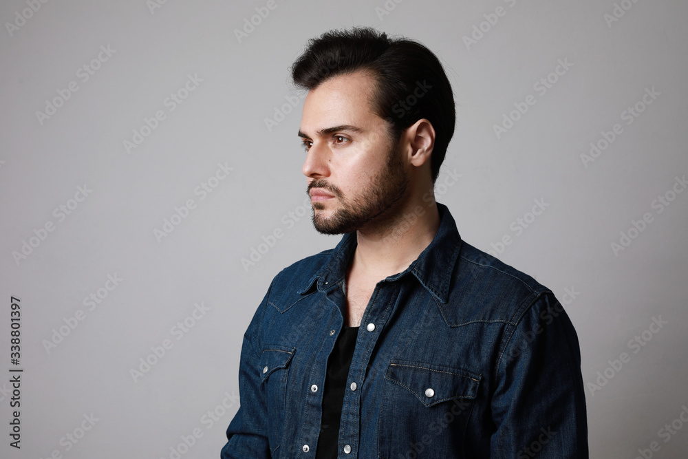 Close-up portrait of 30-year-old man standing over grey background in denim shirt. Copy-space. Studio shot. Close-up portrait of 30-year-old man standing over grey background in denim shirt. Copy-space. Studio shot.