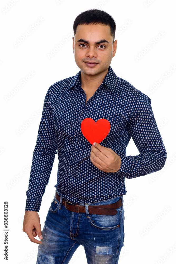 Studio shot of young happy Indian man holding red heart isolated against white background Studio shot of young happy Indian man holding red heart isolated against white background