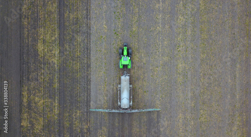 Konstfotografi agriculture: tractor with slurry tanker on a field, aerial view