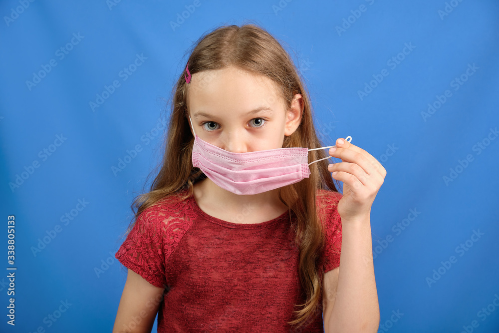 Young long-haired girl in a protective medical mask on a blue background, place for text Young long-haired girl in a protective medical mask on a blue background, place for text
