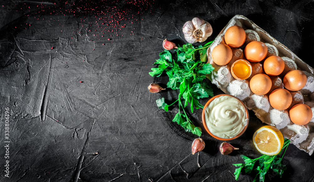 Mayonnaise with eggs, parsley and garlic cloves on dark background