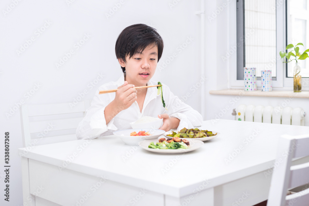 Handsome Asian boy eating with chopsticks