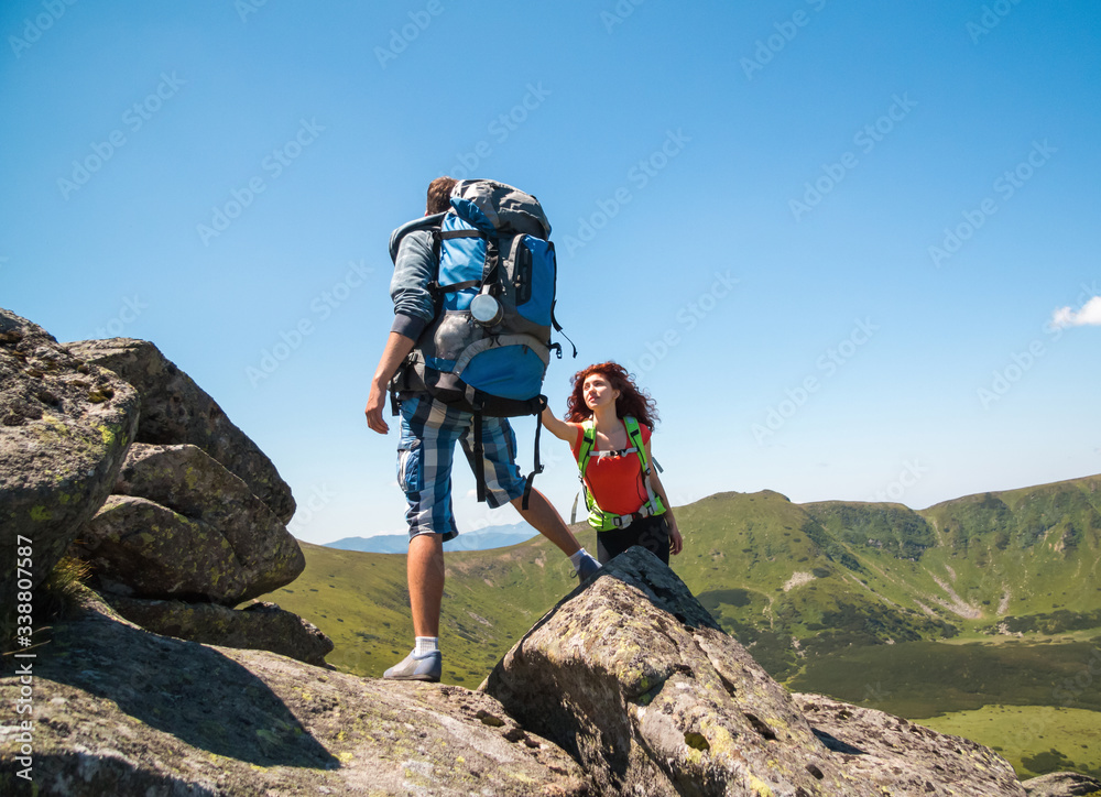 Close-up of loving couple hikers climbing up on the peak of mountain. Climbing, Helps and Team work concept