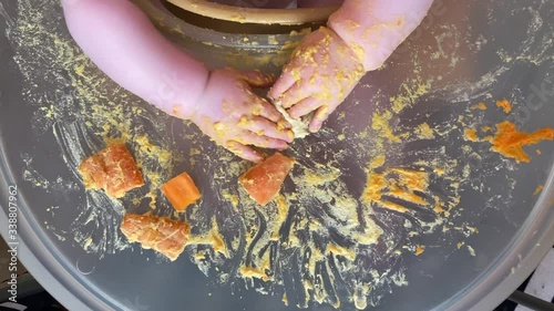 hands of a baby making a mess at meal time during baby led weaning photo