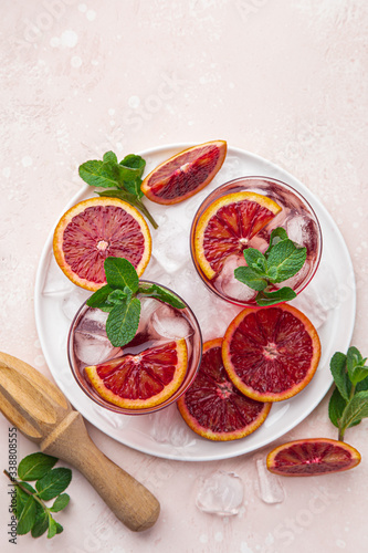 red blood orange cocktail with ice and fresh mint  top view  pink  background