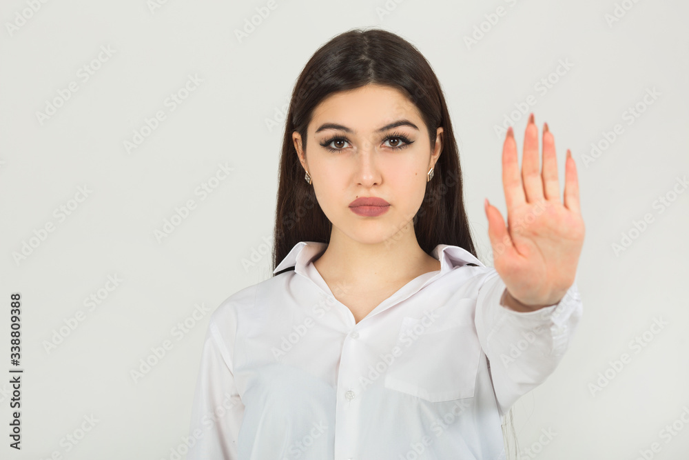 beautiful young woman in a white shirt on a white background with hand gesture beautiful young woman in a white shirt on a white background with hand gesture