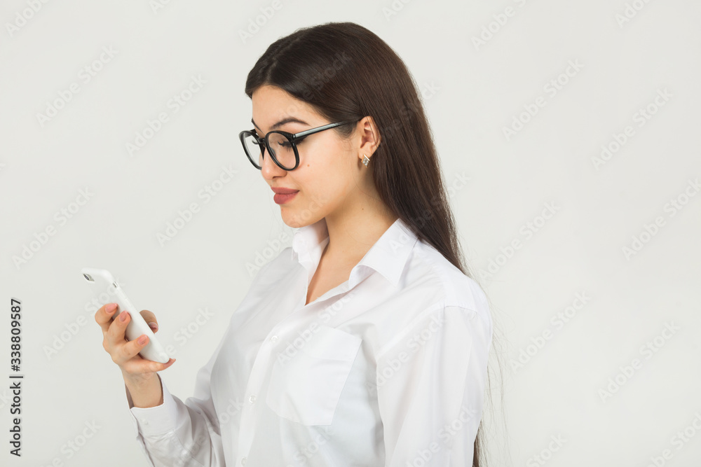 beautiful young woman in glasses on a white background with a phone beautiful young woman in glasses on a white background with a phone