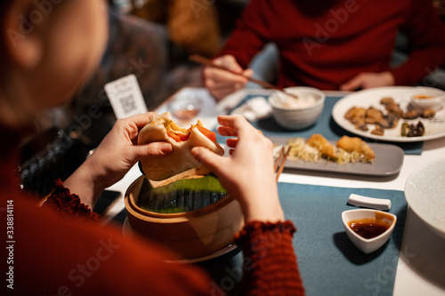 A couple is eating in a chinese restaurant. Close-up of hands, rear view. life style, natural light