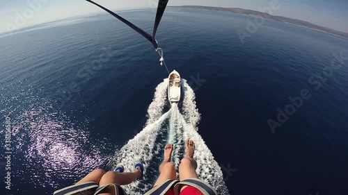 Parasailing landing approach speed motorboat POV young couple legs over blue sea. Amazing Adriatic vacation holiday honeymoon in Croatia