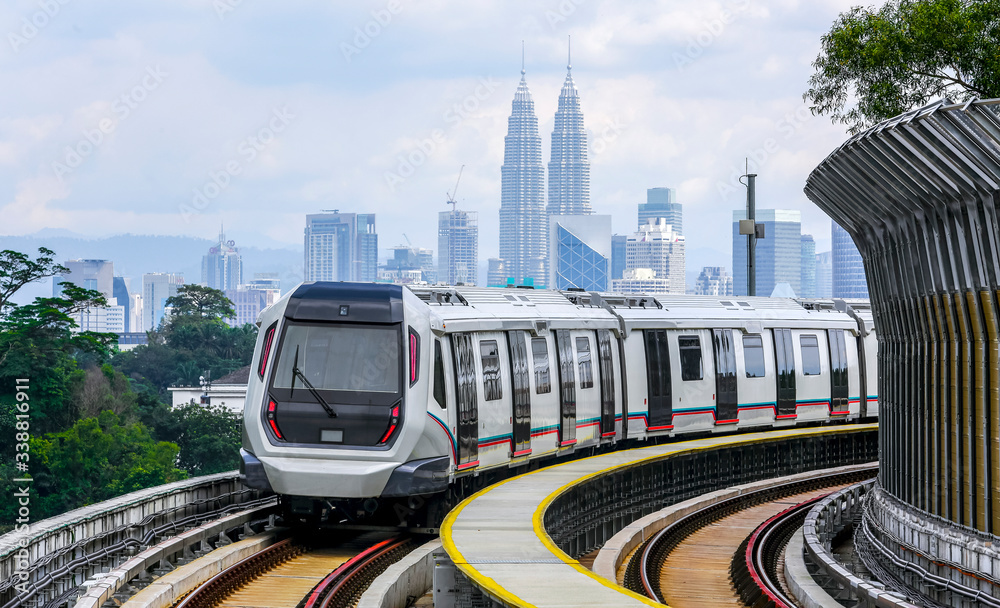 Obraz premium Malaysia Mass Rapid Transit (MRT) train with a background of Kuala Lumpur cityscape. People commute with MRT as transportation to work, school, travel, and shopping.