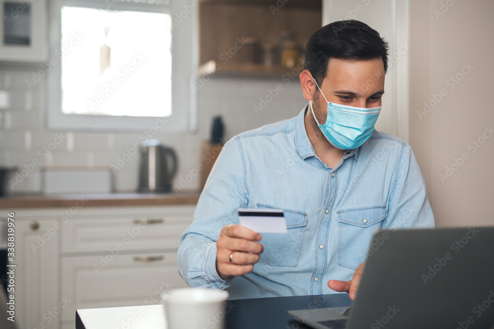 Man holding credit card while wearing mask due to virus pandemic.