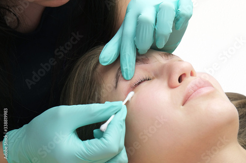 Professional beautician treatment concept. Eyelash lamination  extension performed on beautiful model. Close up portrait  young woman getting eyebrow threading  painting  macroblade shaping procedure.