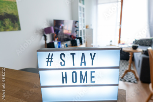 Lightbox sign with hashtag; Stay Home against the background of the interior of the apartment.