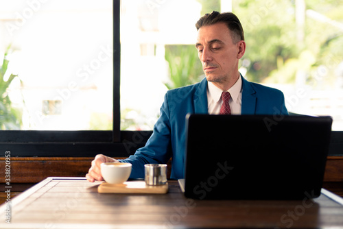 Mature handsome Italian businessman relaxing at the coffee shop