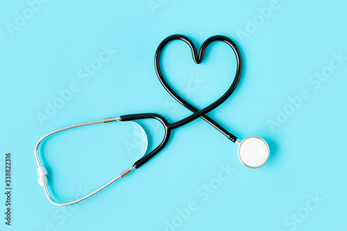 Stethoscope forming a heart on pastel blue background. Medicine and health concept.