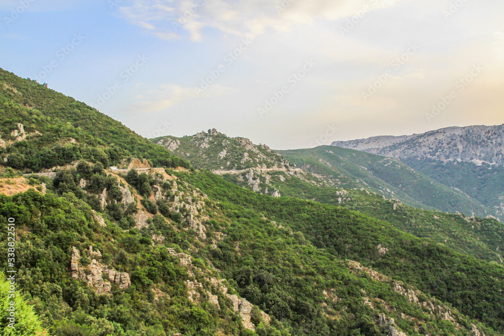 Landscape of Sardinia, Italy, with road along green mountain range and warm sunlight