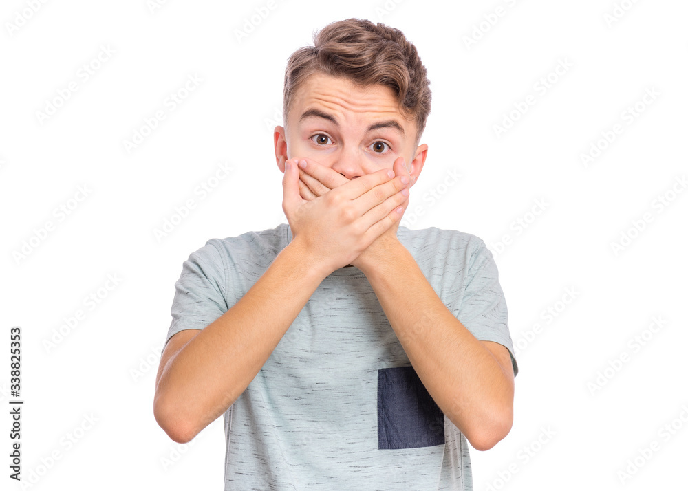 Portrait of amazed teen boy covers mouth with hands. Child with in surprise or fright looking at camera. Caucasian cute young teenager, isolated on white background. Speak no evil concept. Portrait of amazed teen boy covers mouth with hands. Child with in surprise or fright looking at camera. Caucasian cute young teenager, isolated on white background. Speak no evil concept.