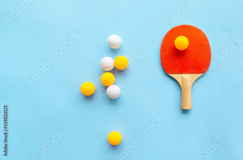 Red racket for table tennis with yellow white balls on blue background. Ping pong sports equipment in minimal style. Flat lay, top view, copy space photo