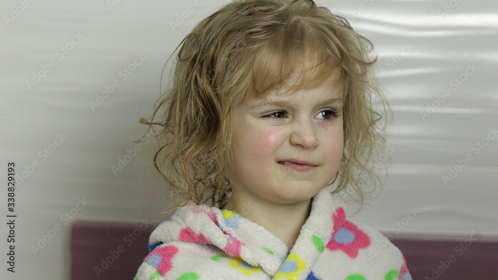 Little girl with wet hair in bathrobe making faces. Smiles after bathing Little girl with wet hair in bathrobe making faces. Smiles after bathing