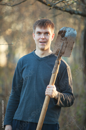 Agronomist handsome strong man with shovel on background of flower beds