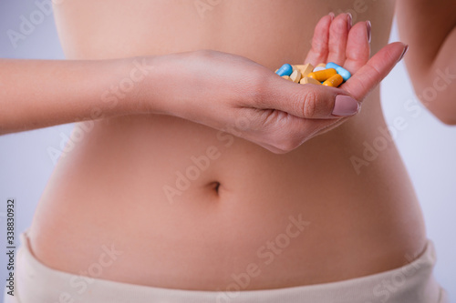 Pills with probiotics on the background of the female abdomen. © galina_kovalenko