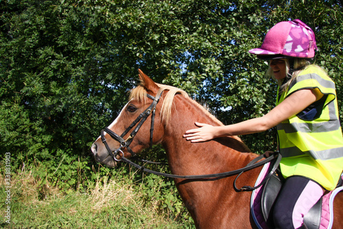 Young woman riding horse wearing high-viz.