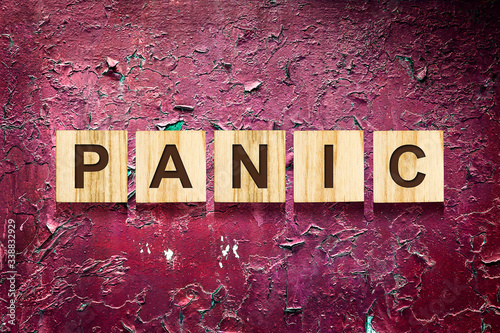 Panic. The inscription on wooden blocks against the background of a red cracked wall. Panic during a pandemic. Health. Business.