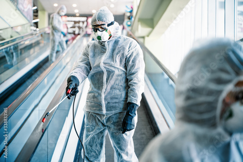 Disinfectant worker in protective suit making disinfection in shopping centre, to control an outbreak of virus in the city photo
