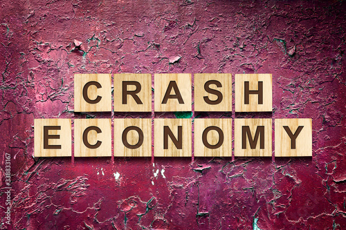Crash. Economy. The inscription on wooden blocks against the background of a red cracked wall. The fall of the economy during the pandemic. Business.
