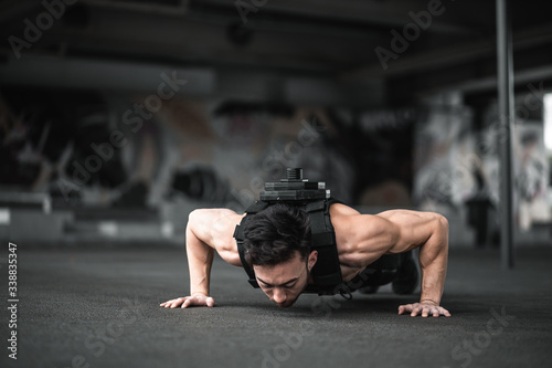 Man during workout in the gym Concept: power, strength, healthy lifestyle, sport. Powerful attractive muscular Man CrossFit trainer do battle workout with ropes at the gym. Young man exercising using