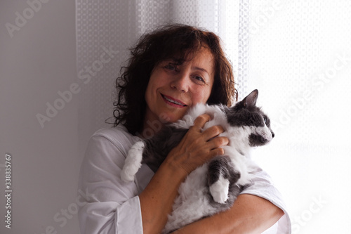 Woman and cat in the hands. Beautiful adult lady holds a fluffy pet in her arms. Friendly relations of animal and human. Free space for text. Soft focus