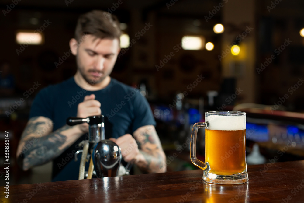Bartender pouring from tap fresh beer into the glass in pub
