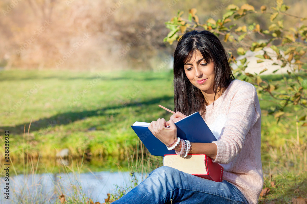 Fototapeta premium Beautiful Woman Studying Outdoor on a Lake Background 
