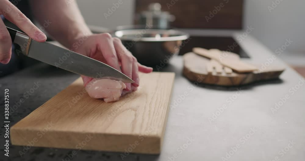 Slow motion man hands slicing chicken fillet on oak board Slow motion man hands slicing chicken fillet on oak board