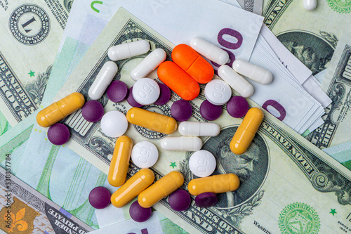 colorful medicine tablets pills on the money background. Pandemic economic crisis