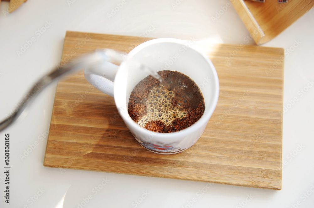 Brewing coffee in mug. Pouring water from gooseneck kettle into cup with freshly ground coffee top view Brewing coffee in mug. Pouring water from gooseneck kettle into cup with freshly ground coffee top view