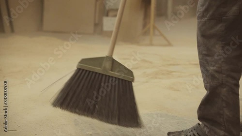 janitor sweeping wood dust and sawdust with a broom