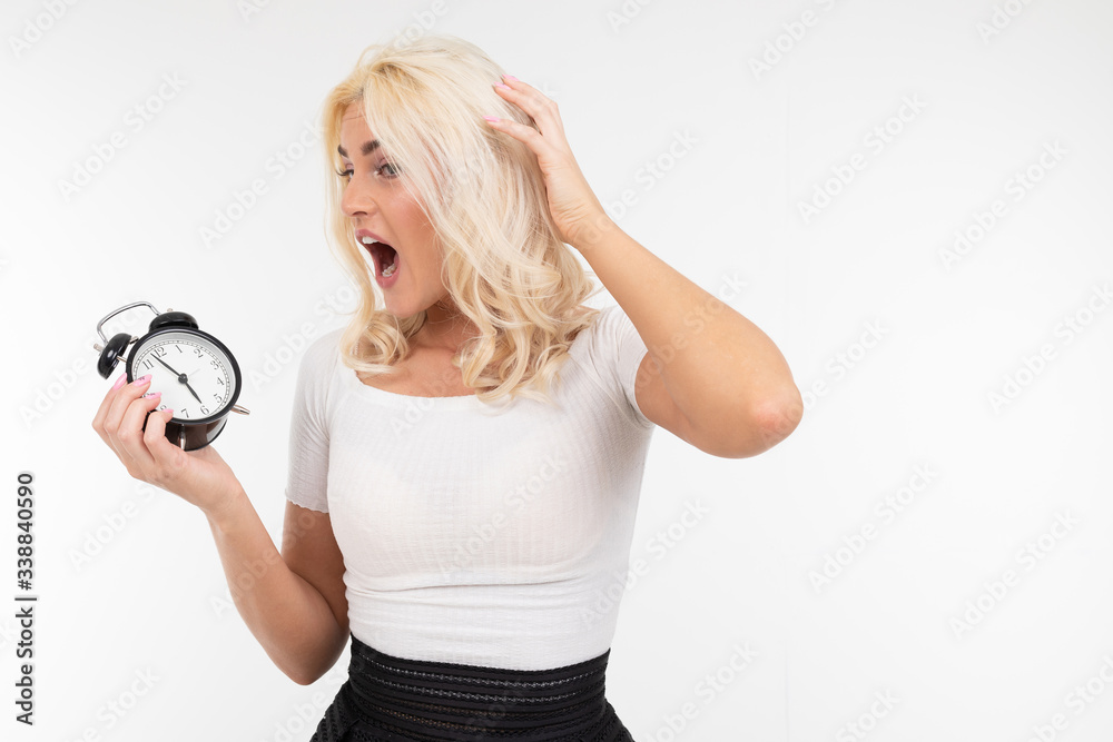 sexy lady in a white t-shirt holds an alarm clock with a large dial on a white background with copy space sexy lady in a white t-shirt holds an alarm clock with a large dial on a white background with copy space