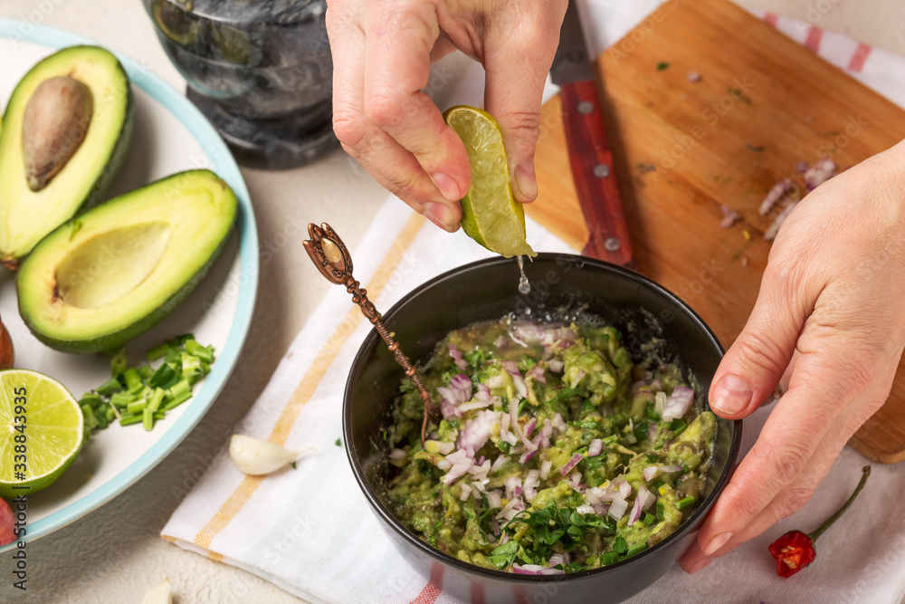 Process of preparation of a Mexican sauce guacamole. Woman squeeze juice from lime fruit Process of preparation of a Mexican sauce guacamole. Woman squeeze juice from lime fruit